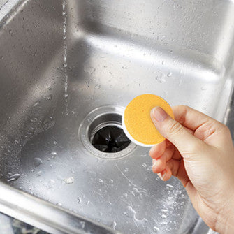 An unwrapped cleaning tablet being placed into the disposal